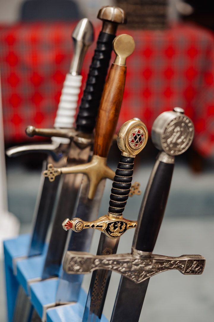 Collection of decorative medieval swords with ornate handles displayed in a blue holder.