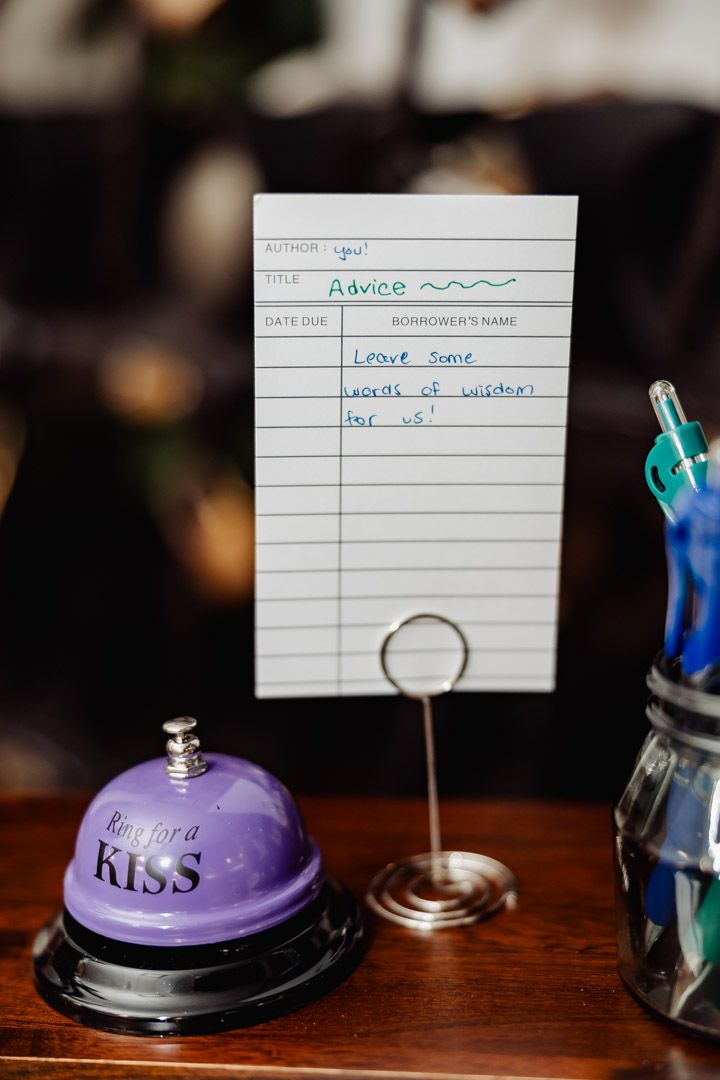 Vintage style advice card holder with purple kiss bell on wooden surface.
