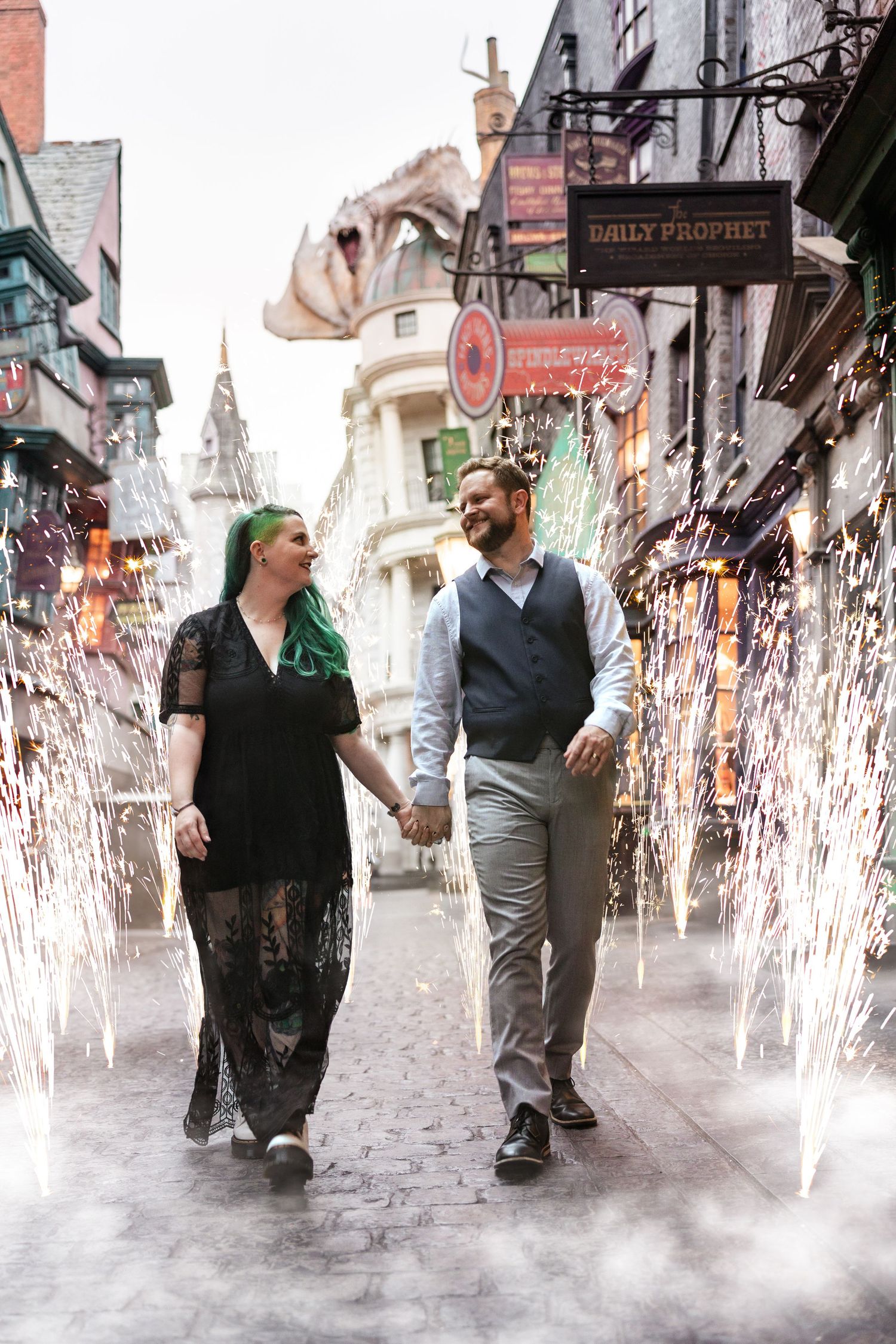 A couple strolls through a cobblestone street with magical sparkling fountains in a whimsical setting.