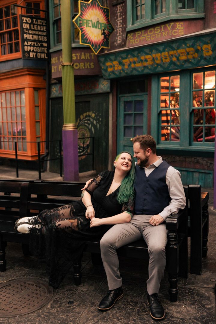 Couple sitting on a bench laughing together in the colorful Diagon Alley at Universal Studios.