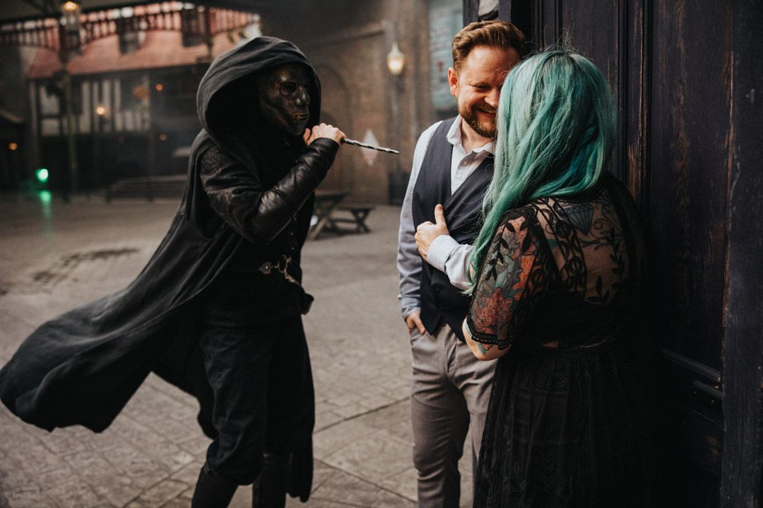 Death Eater character interacting with a couple at the Wizarding World of Harry Potter theme park.