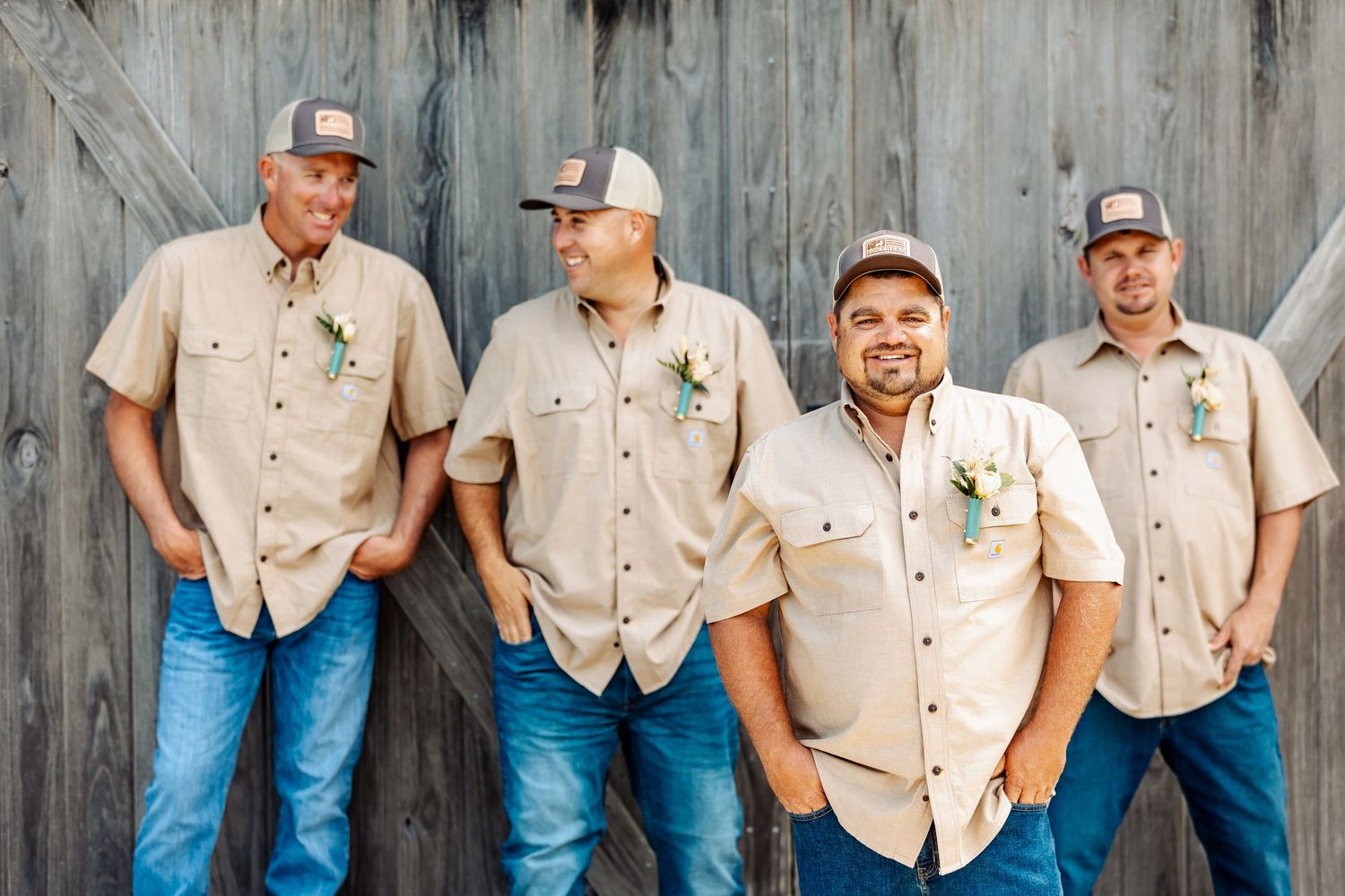 Casual group portrait against weathered barn wood wearing matching khaki shirts.