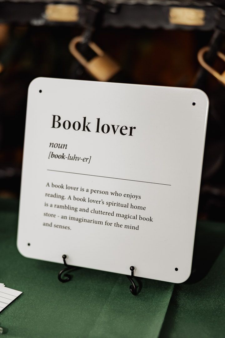 Decorative sign displaying the definition of 'Book lover' on green tablecloth.