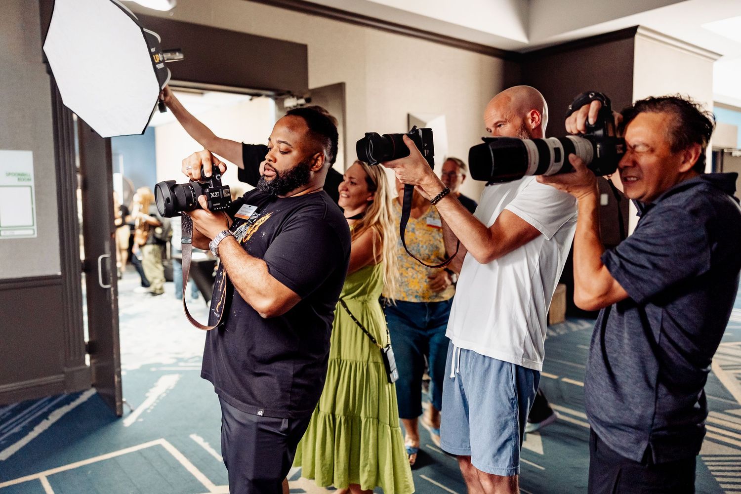 Professional photographers with cameras lined up taking photos at an event.