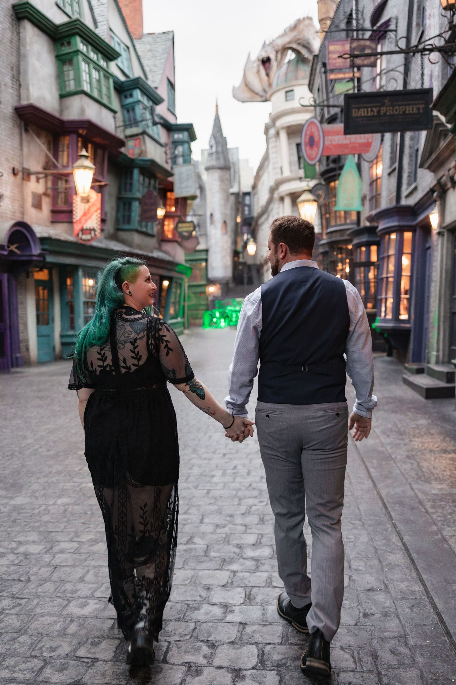 A couple walks hand in hand through a magical cobblestone street with twinkling lights.