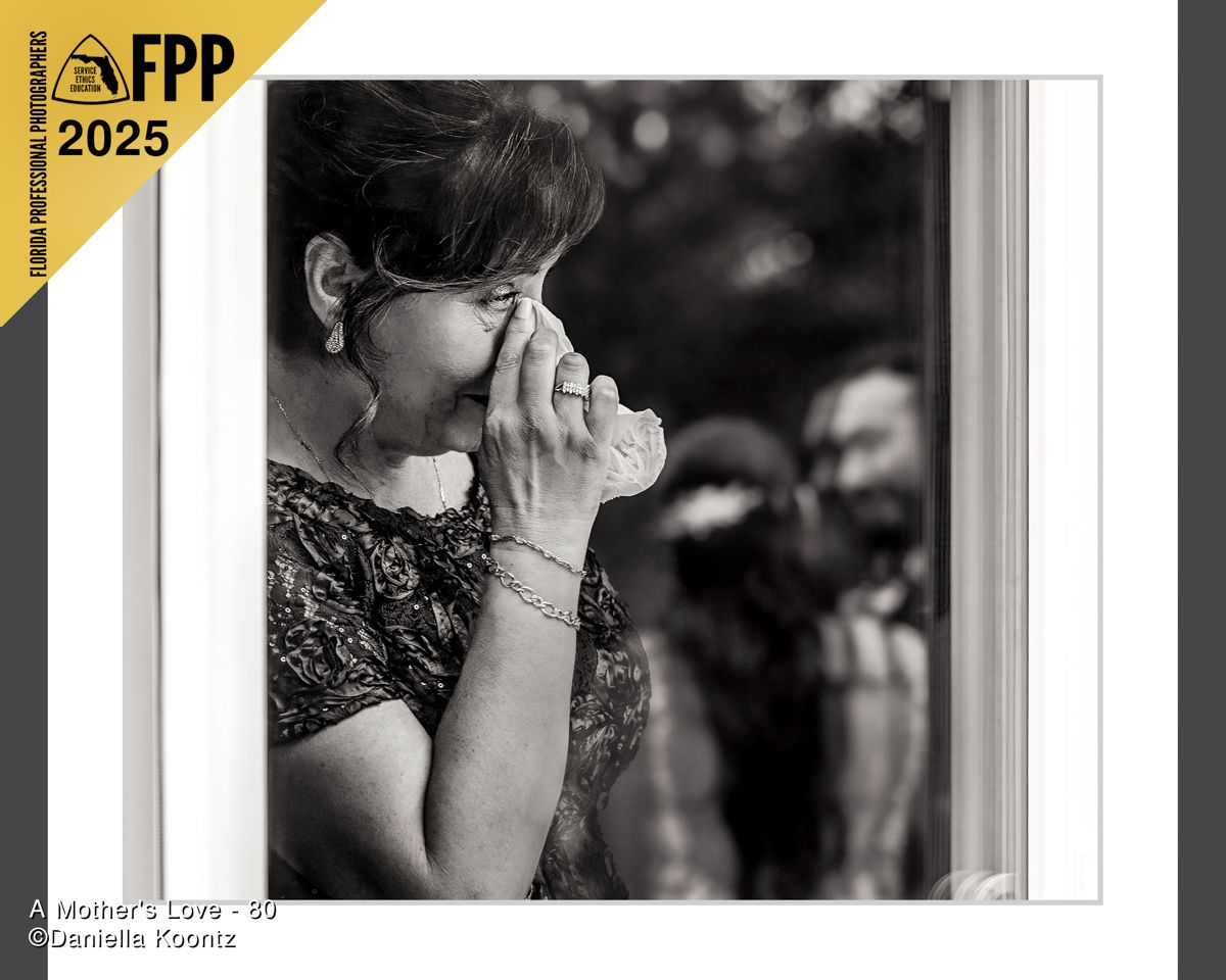 Black and white FPP 2025 award-winning photo of emotional woman wiping tears at window.