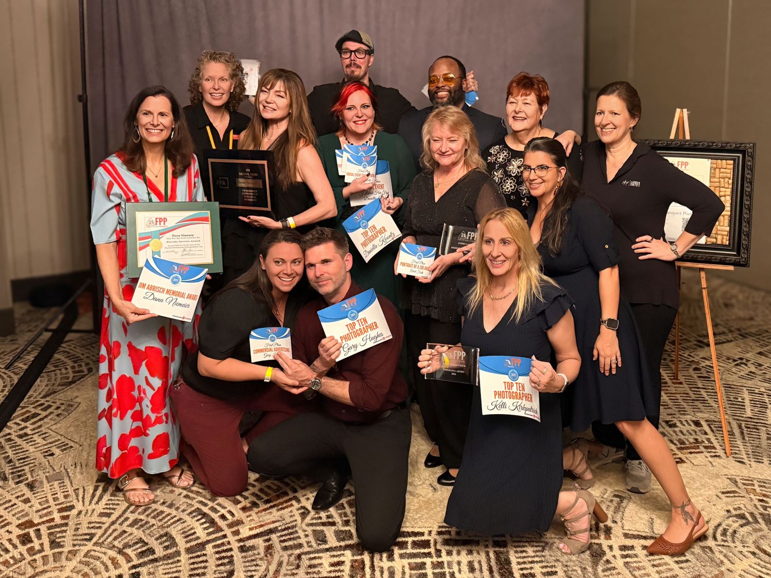 Group of professionals posing with awards and plaques at a corporate recognition ceremony event.