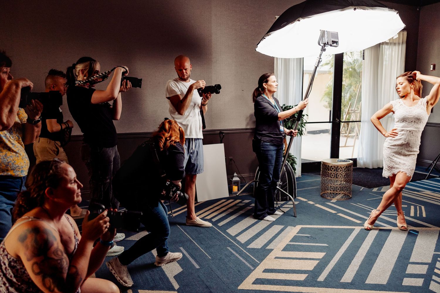 Photography workshop in studio with multiple photographers capturing poses under professional lighting.