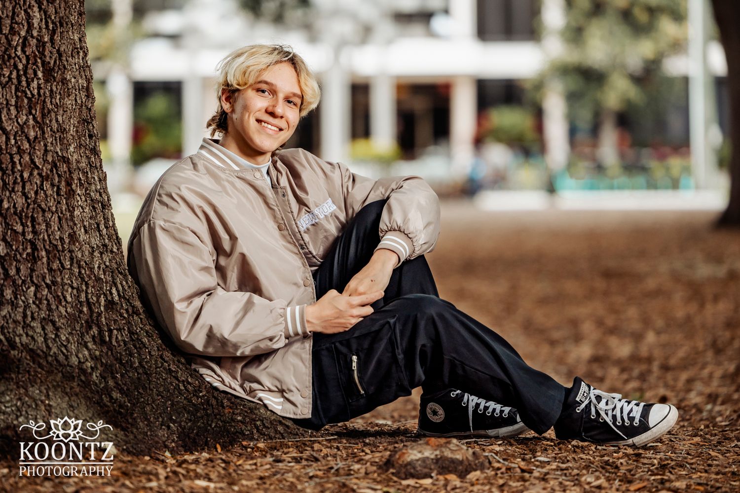 Casual portrait session in a park setting with autumn leaves on the ground.