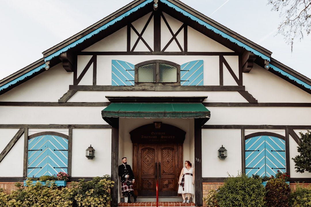 A tudor-style wedding venue with white walls, blue shutters, and dark wood trim details.