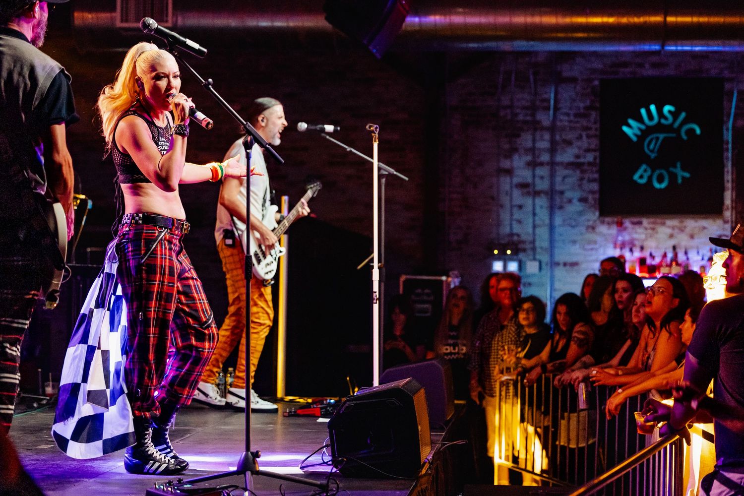 Female rock singer in plaid pants performs at Music Box venue with guitarist before a crowd of fans.