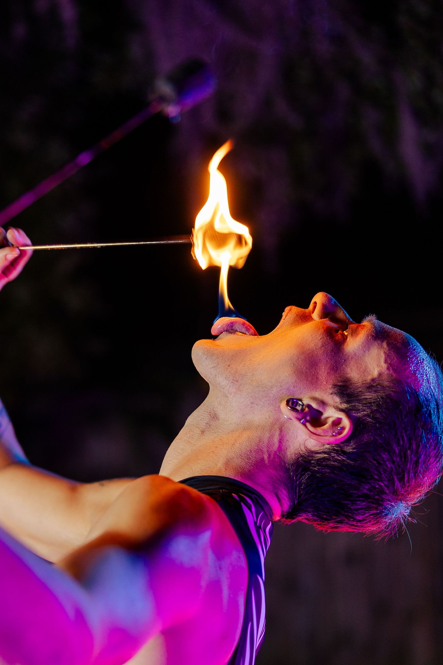 Close-up of a fire eater holding a flaming torch to their mouth during an outdoor night performance.