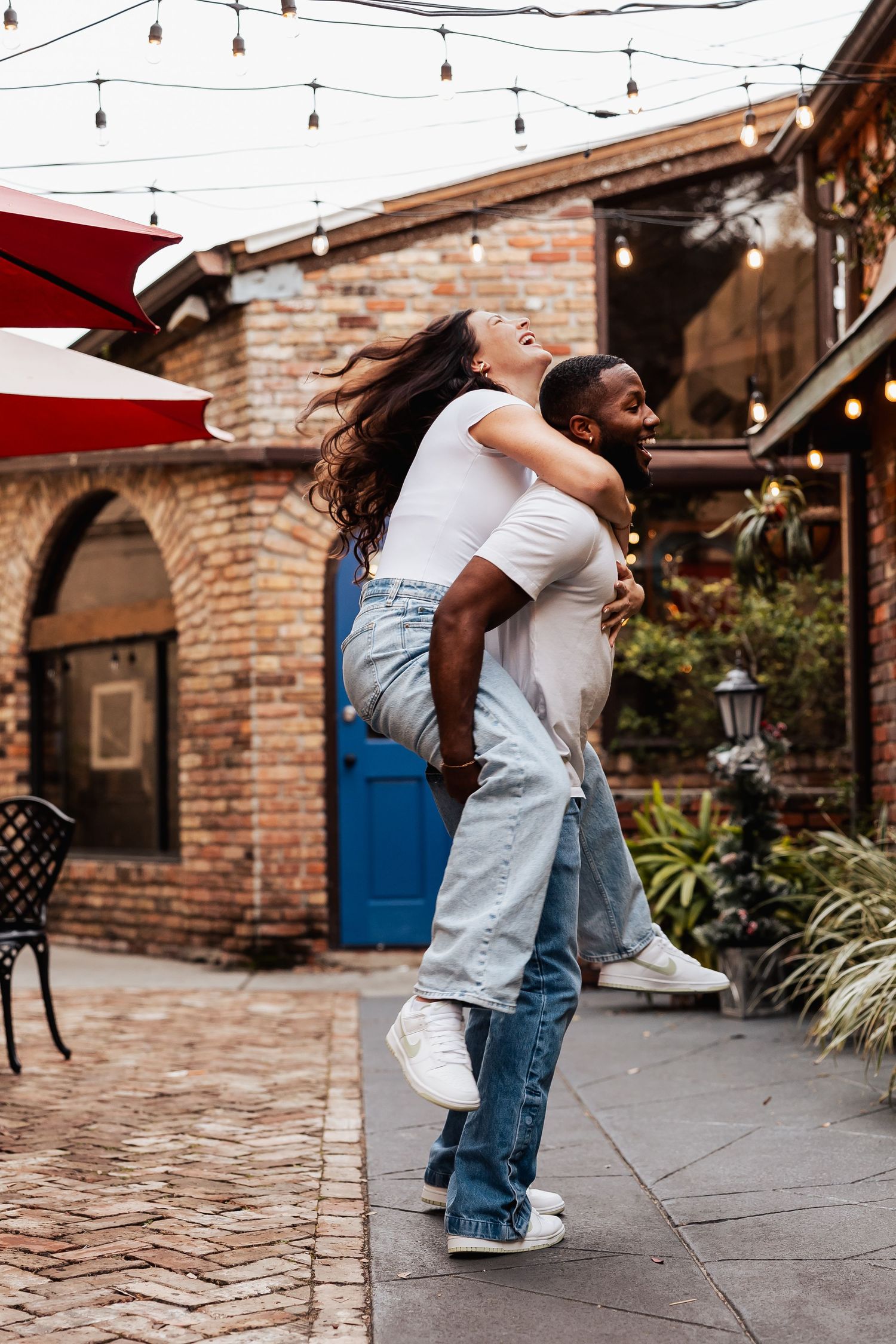Happy moment captured in a romantic outdoor setting with brick walls and string lights overhead.