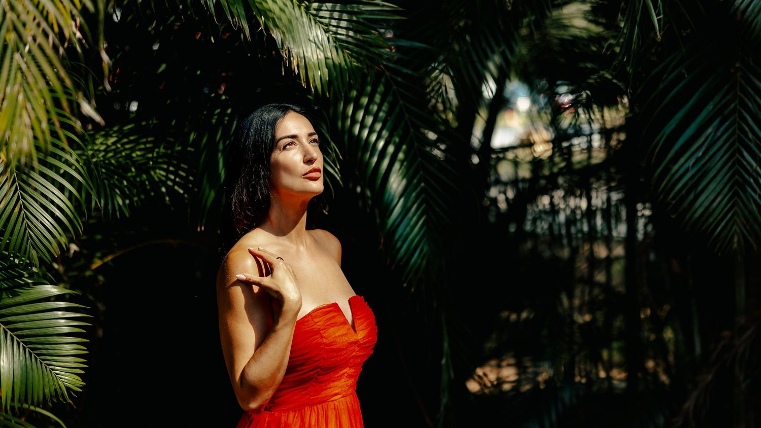 Elegant outdoor portrait with natural light filtering through palm leaves.