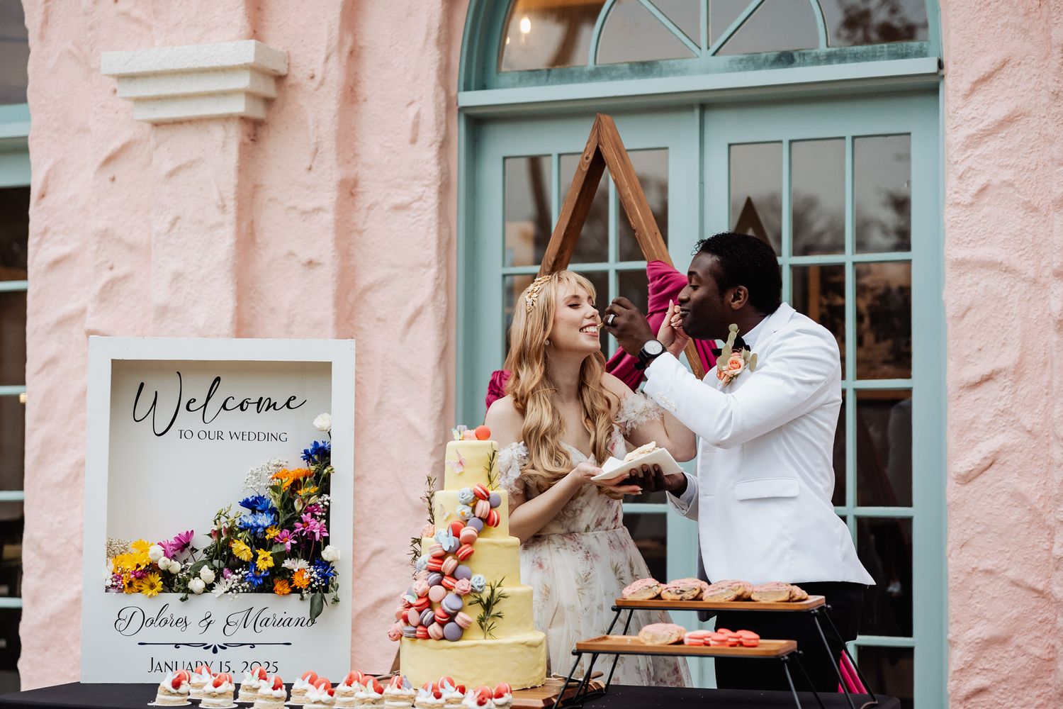 A joyful couple shares a sweet celebration moment while cutting their wedding cake together outdoors.