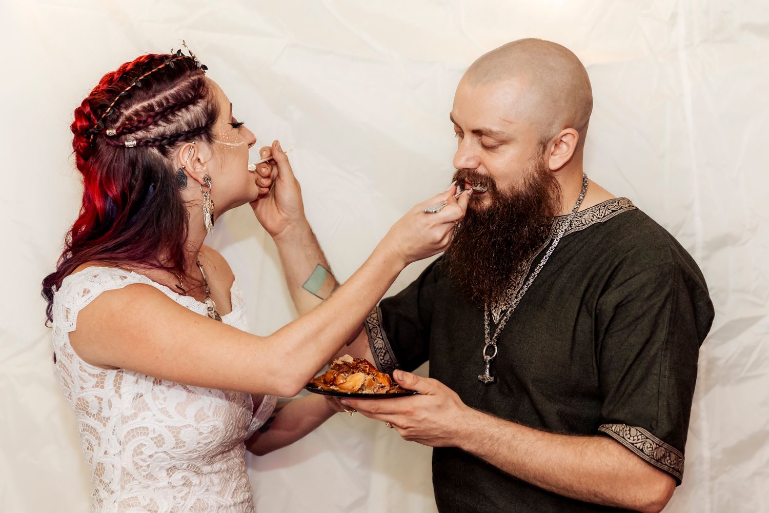 Couple playfully feeds each other dessert during their wedding celebration.