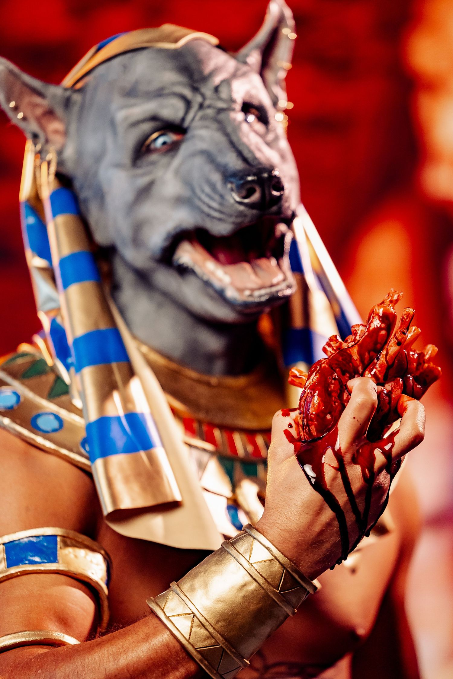 Detailed Anubis cosplay with realistic dog head mask, Egyptian headdress, and bloody prop in hand.