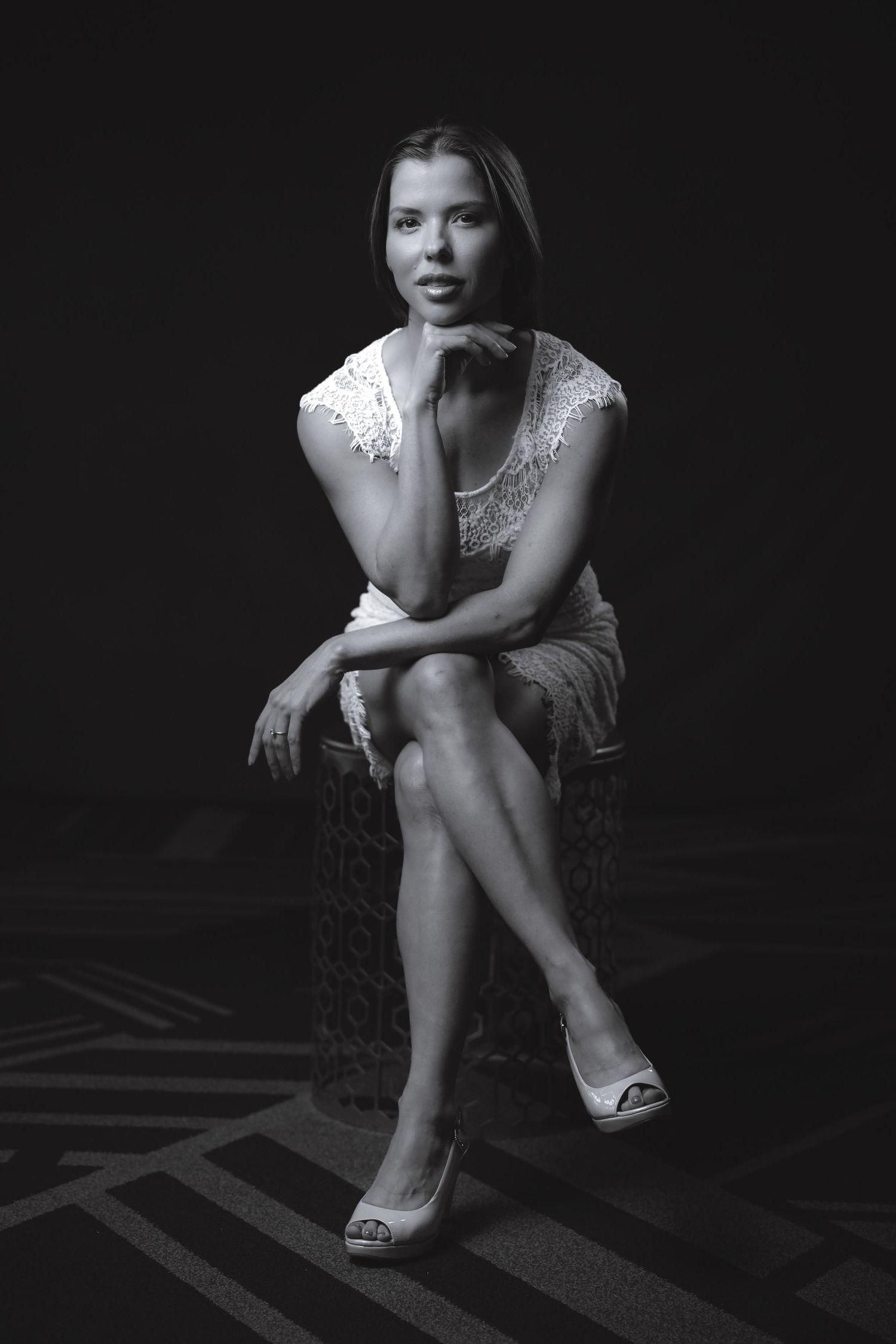 Elegant black and white portrait featuring crossed legs and lace dress details in moody studio lighting.