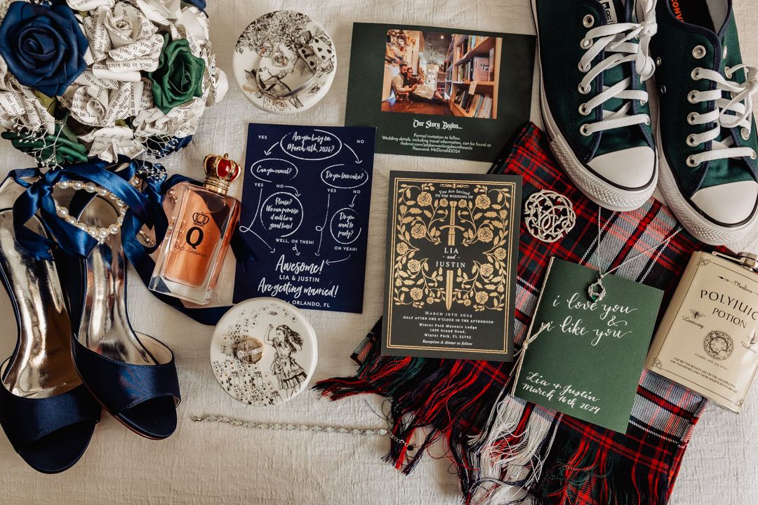 Wedding flat lay featuring navy heels, Converse sneakers, plaid fabric, invitations, and floral bouquet.
