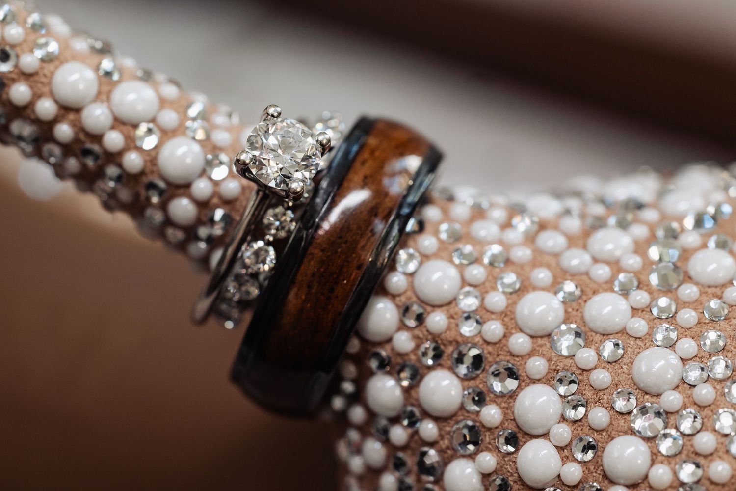 Diamond engagement ring and wooden wedding band resting on pearl-embellished bridal heel.