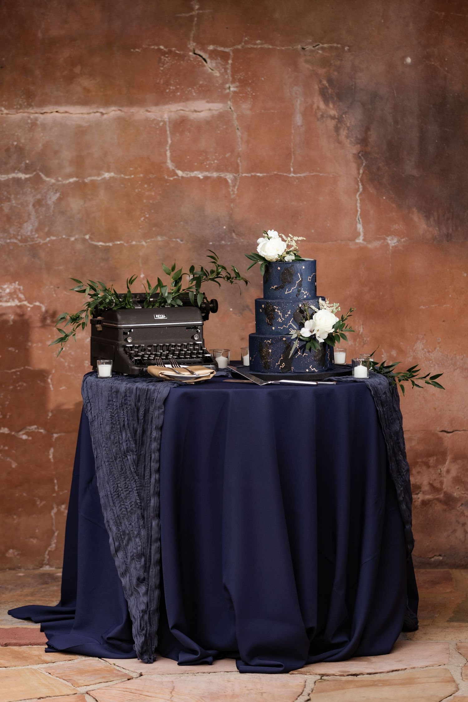 Navy blue celestial wedding cake display table with vintage typewriter decor.