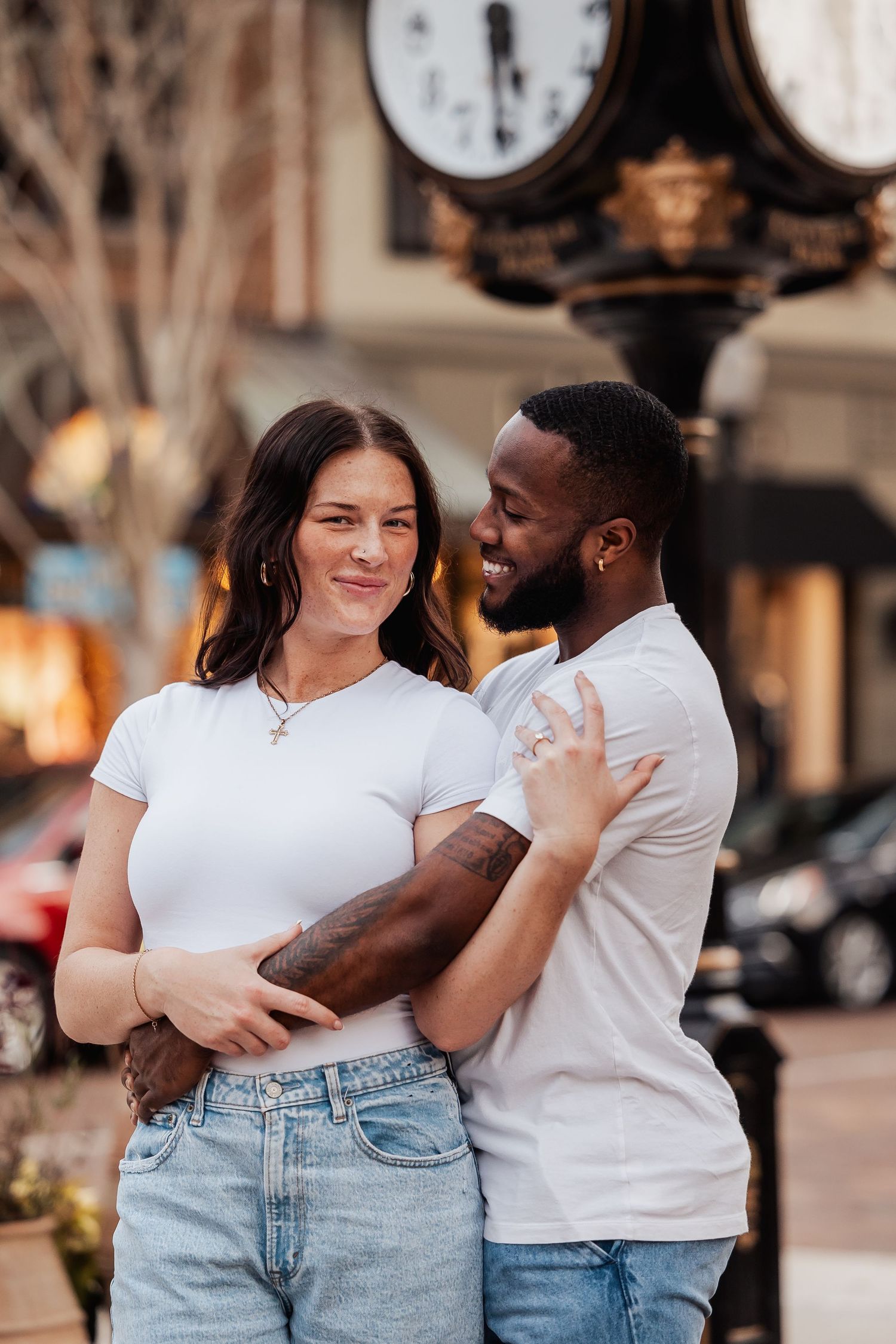 Sweet embrace captured in front of a vintage street clock during golden hour.