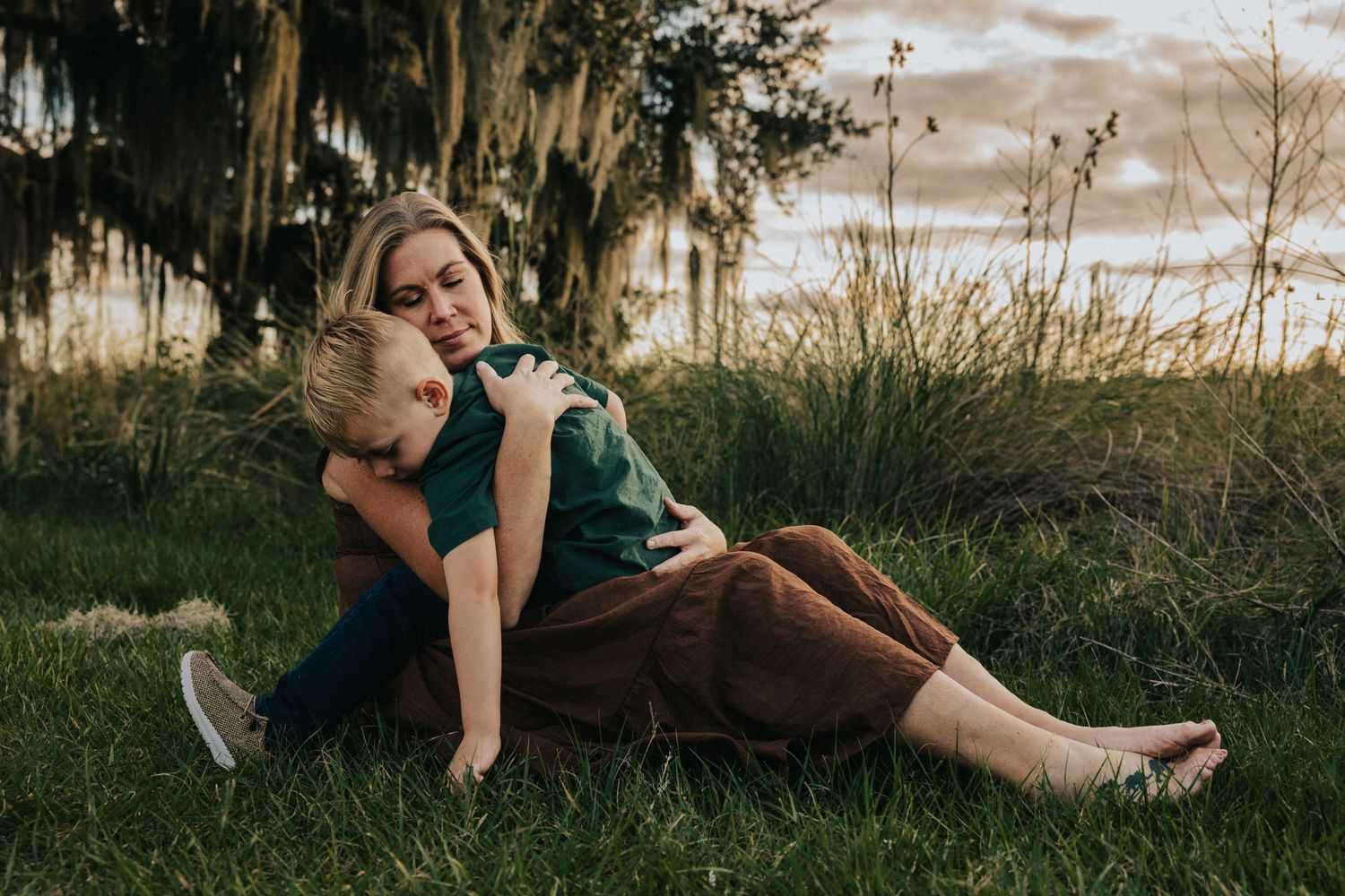 An emotional embrace captured during a golden hour photoshoot with moss-covered trees in the background.