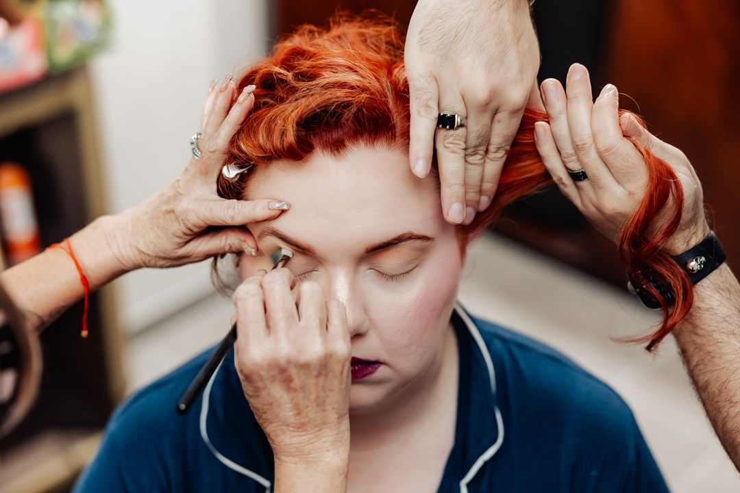 Close up of hands styling red hair during wedding preparation.