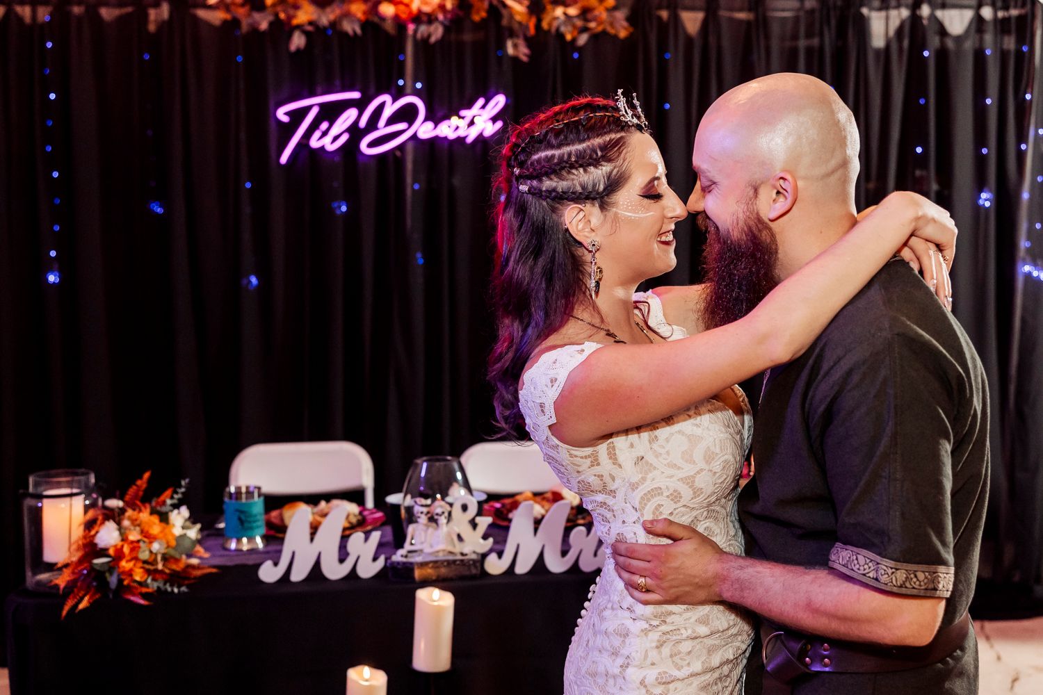 A romantic wedding scene with neon signage and decorative 'Mr & Mrs' text against dark curtains.