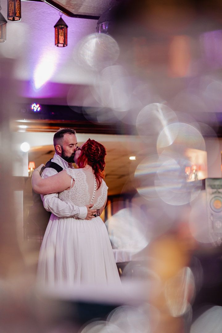 A romantic first dance moment at a wedding reception with purple mood lighting and hanging lanterns.