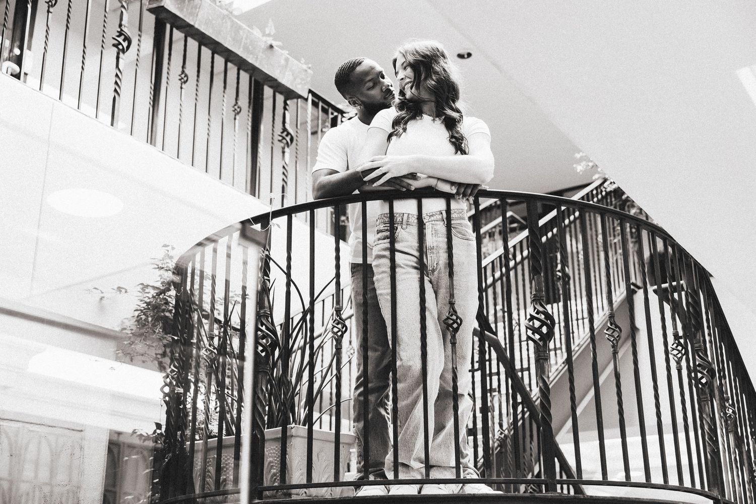 Couple sharing romantic moment on spiral staircase in black and white photography.