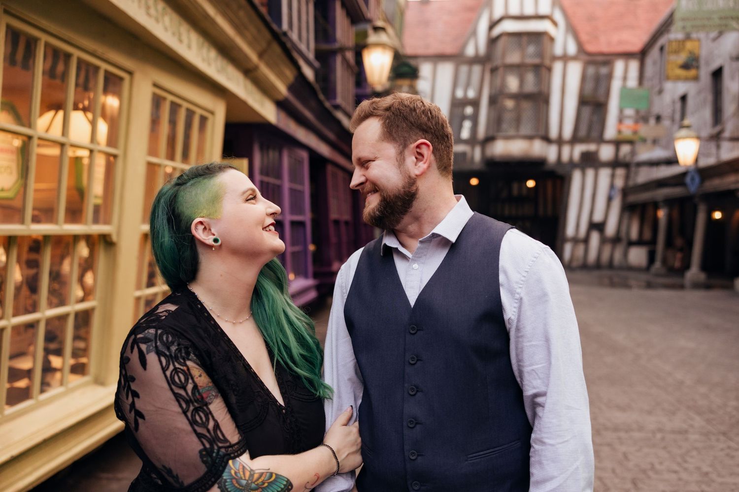 A couple shares a joyful moment in front of historic Tudor-style buildings.