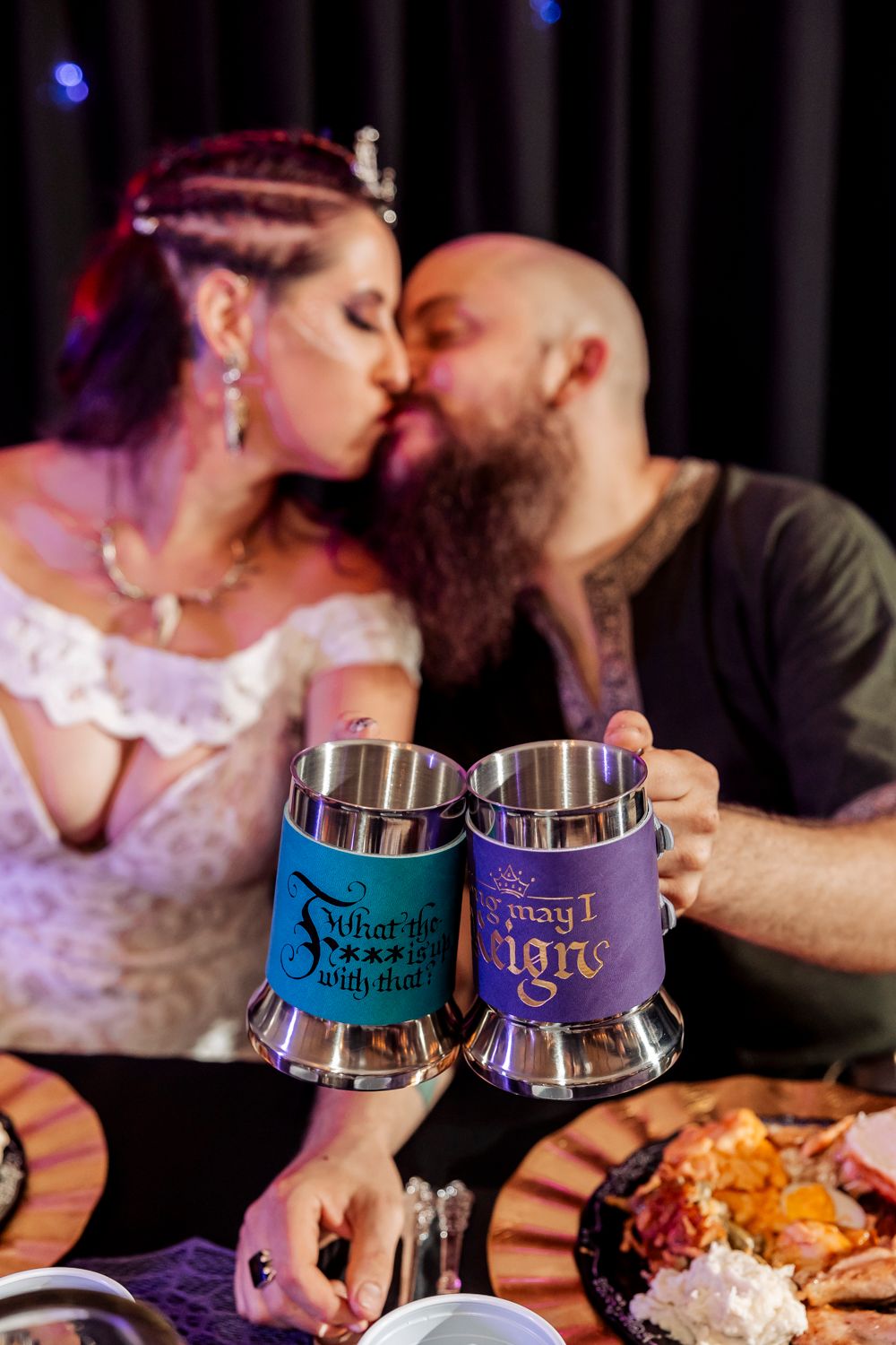 A romantic moment captured with custom medieval-themed drinking steins during a wedding reception.