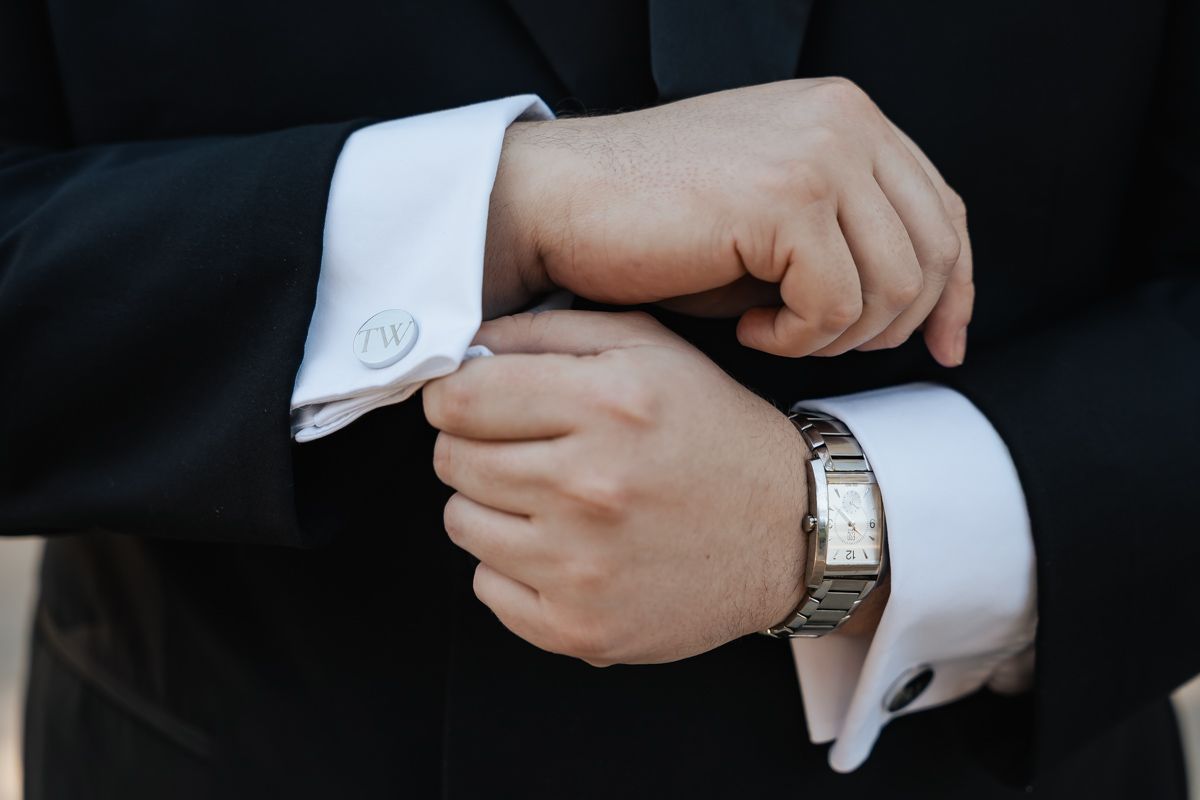 Close-up of hands adjusting formal black suit cuffs and white dress shirt sleeves.