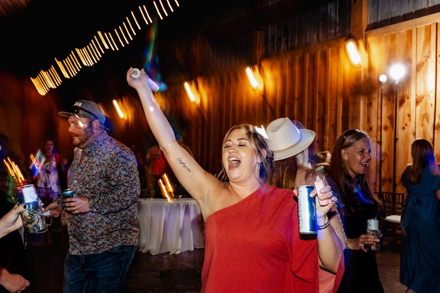 Reception guests dancing with enthusiasm at rustic barn wedding celebration.