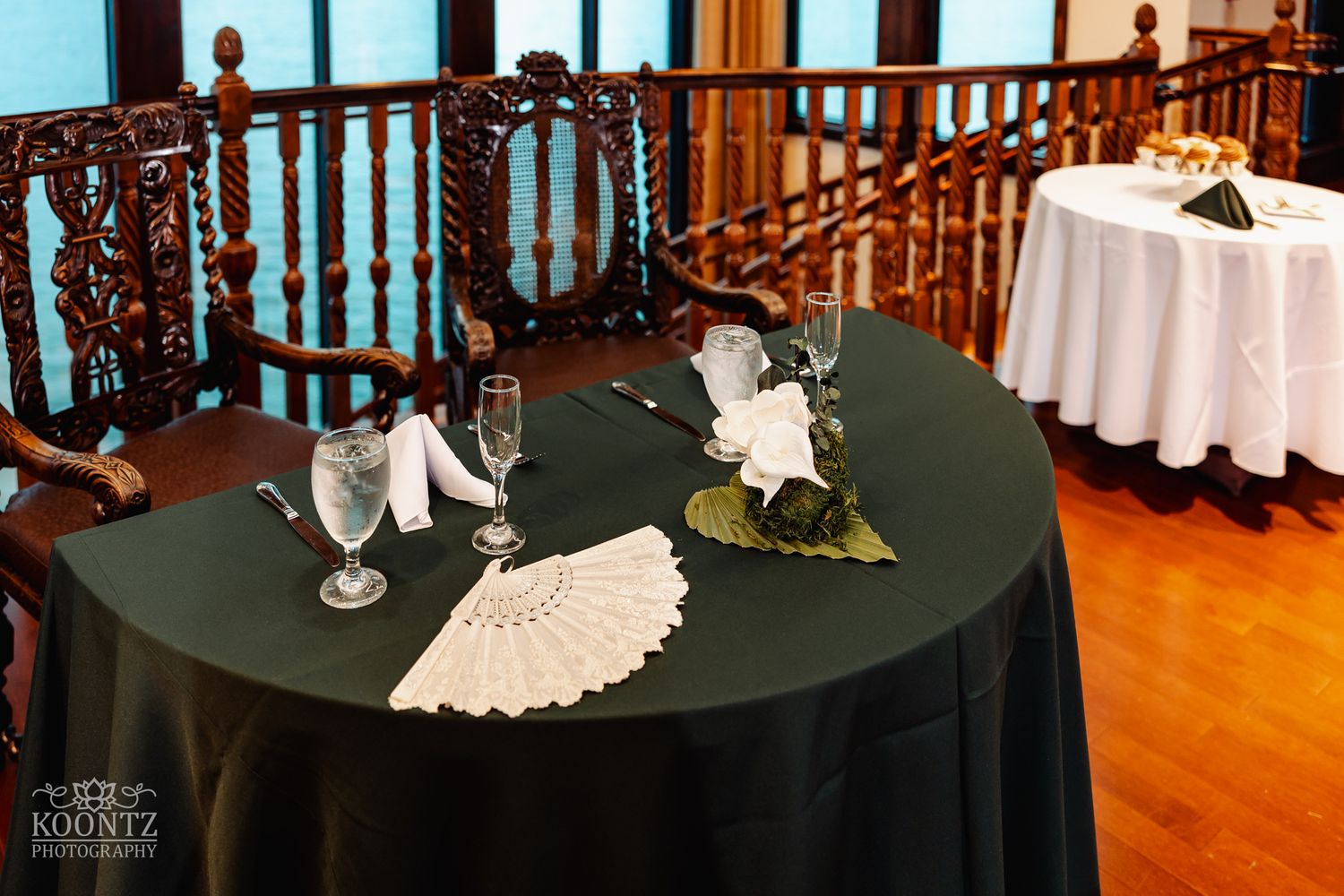 Wedding reception table with black tablecloth featuring delicate white lace decorations and champagne glasses.