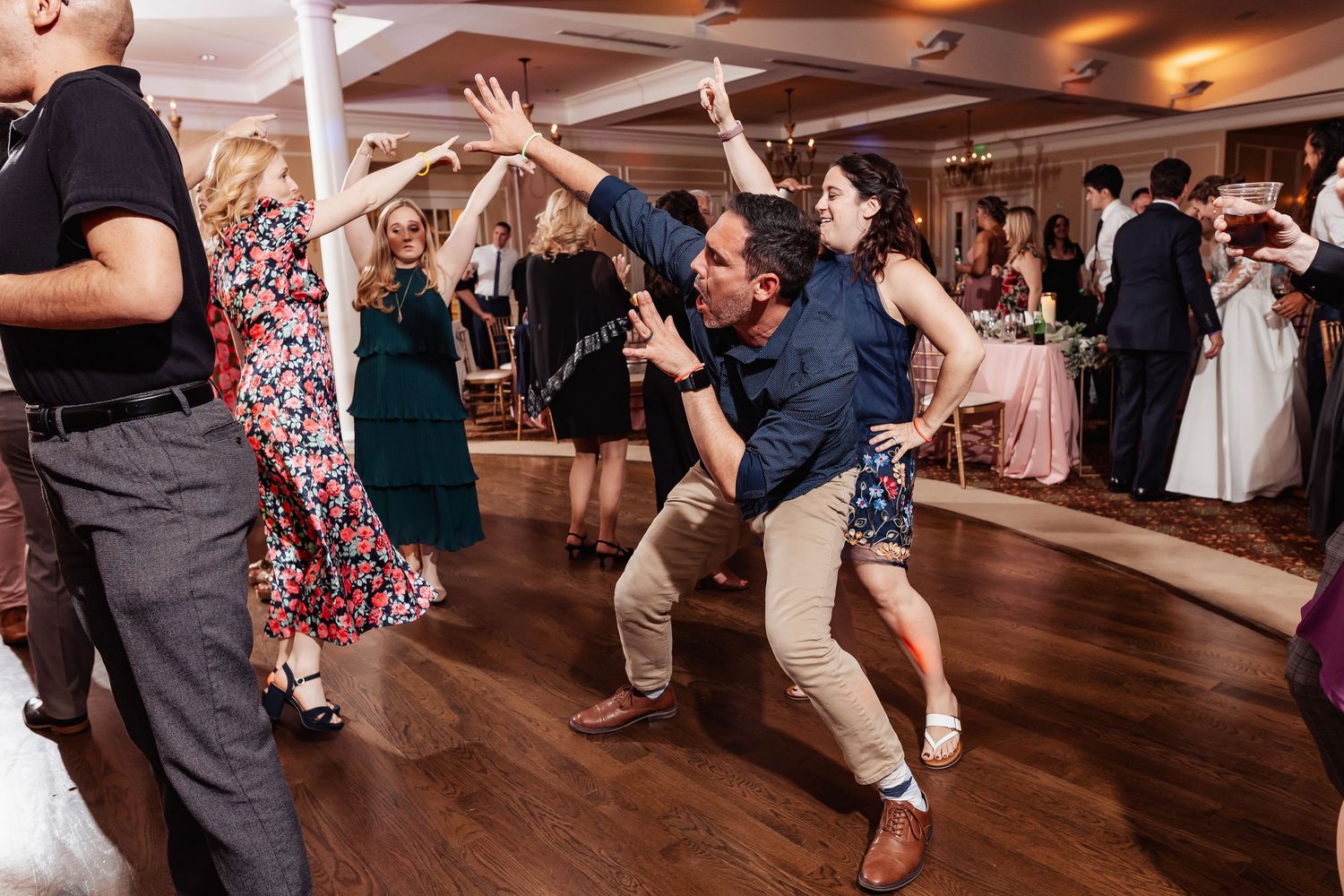 Energetic wedding guests show off dance moves on the reception dance floor during celebrations.