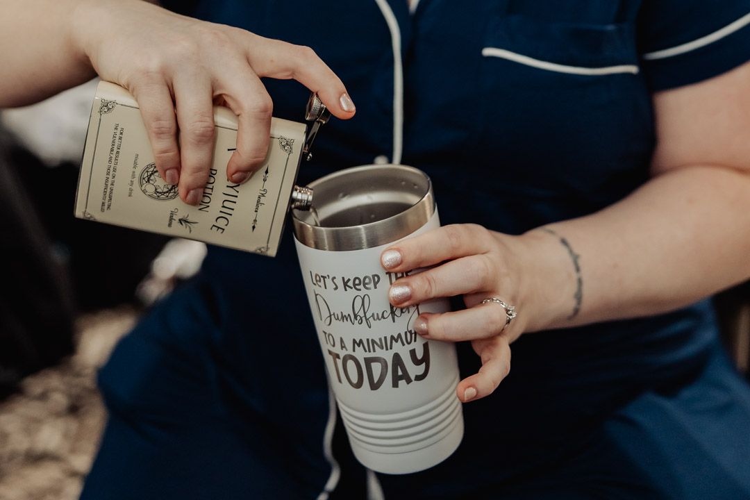 Person putting money into a decorated white travel tumbler.