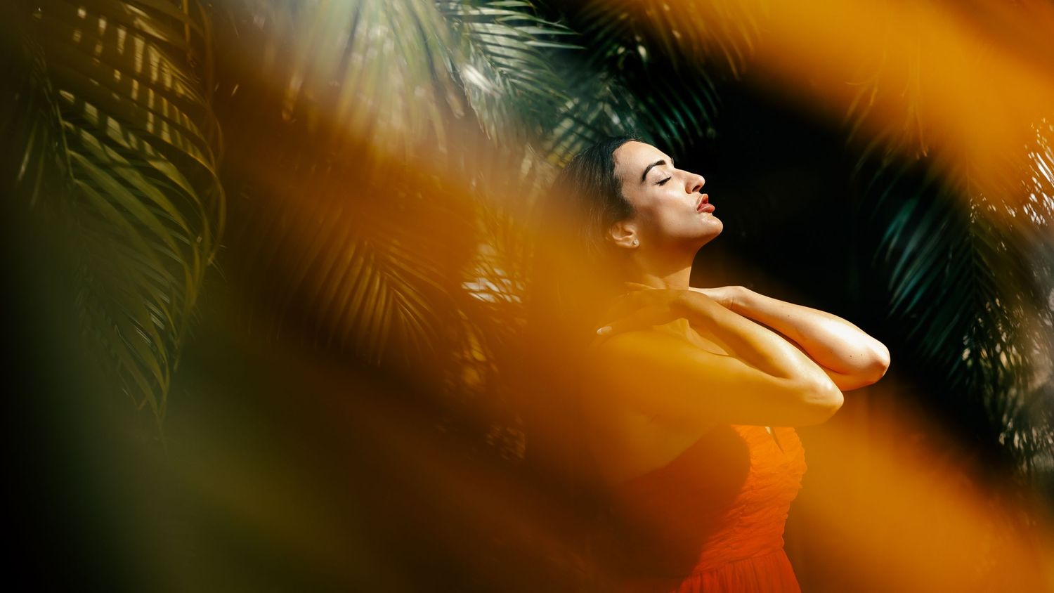 Dreamy portrait through tropical foliage with sunlight creating warm color effects.