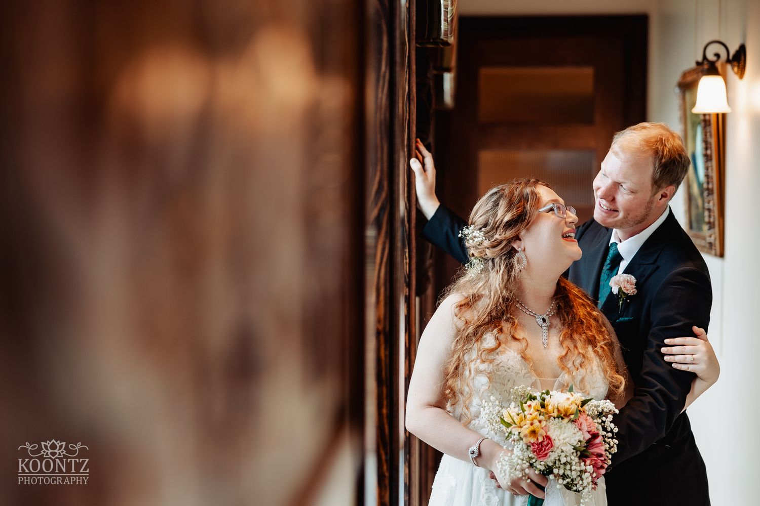 A romantic wedding couple sharing an intimate moment near a wooden banister.