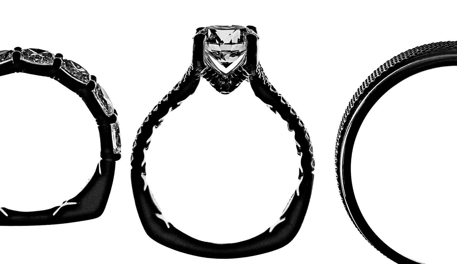Three black and white diamond engagement rings displayed side by side, featuring intricate band details and a solitaire center stone.