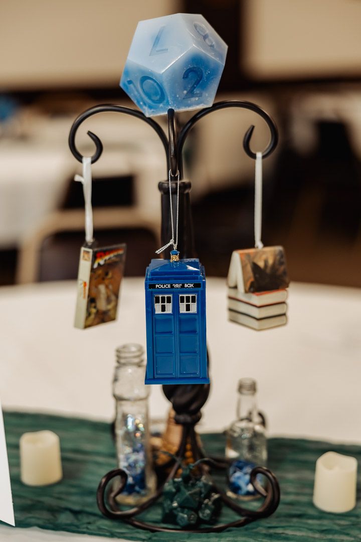 TARDIS ornament display with blue D20 die and miniature books on decorative stand.