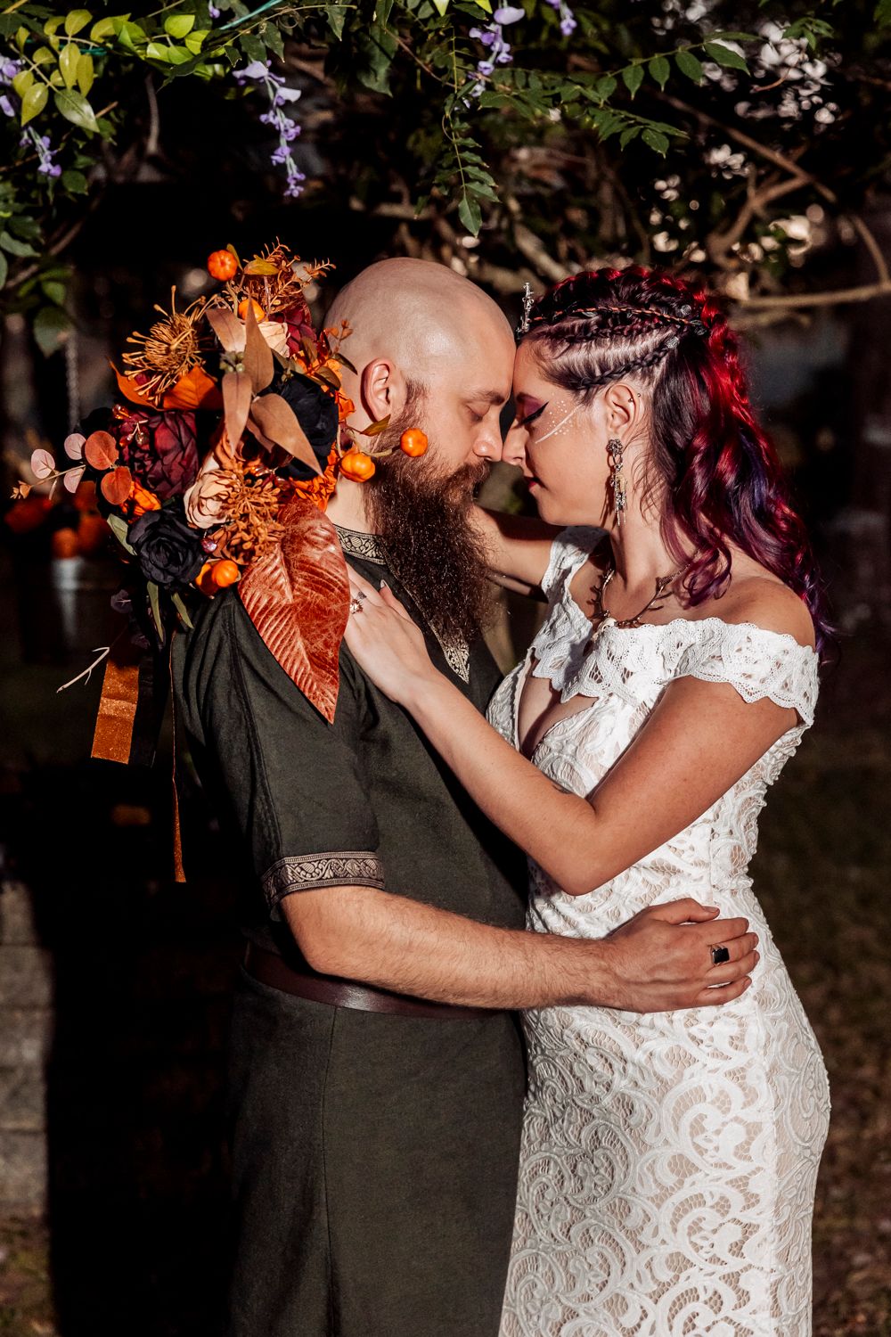 Romantic embrace with orange floral bouquet during outdoor autumn wedding ceremony.