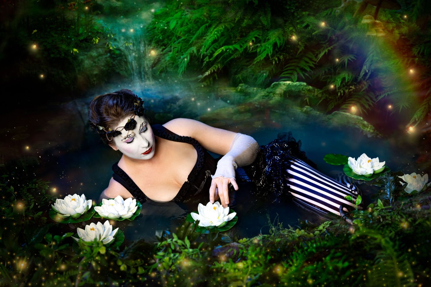 Woman with skull face paint in black dress lying among white water lilies in magical glowing forest.