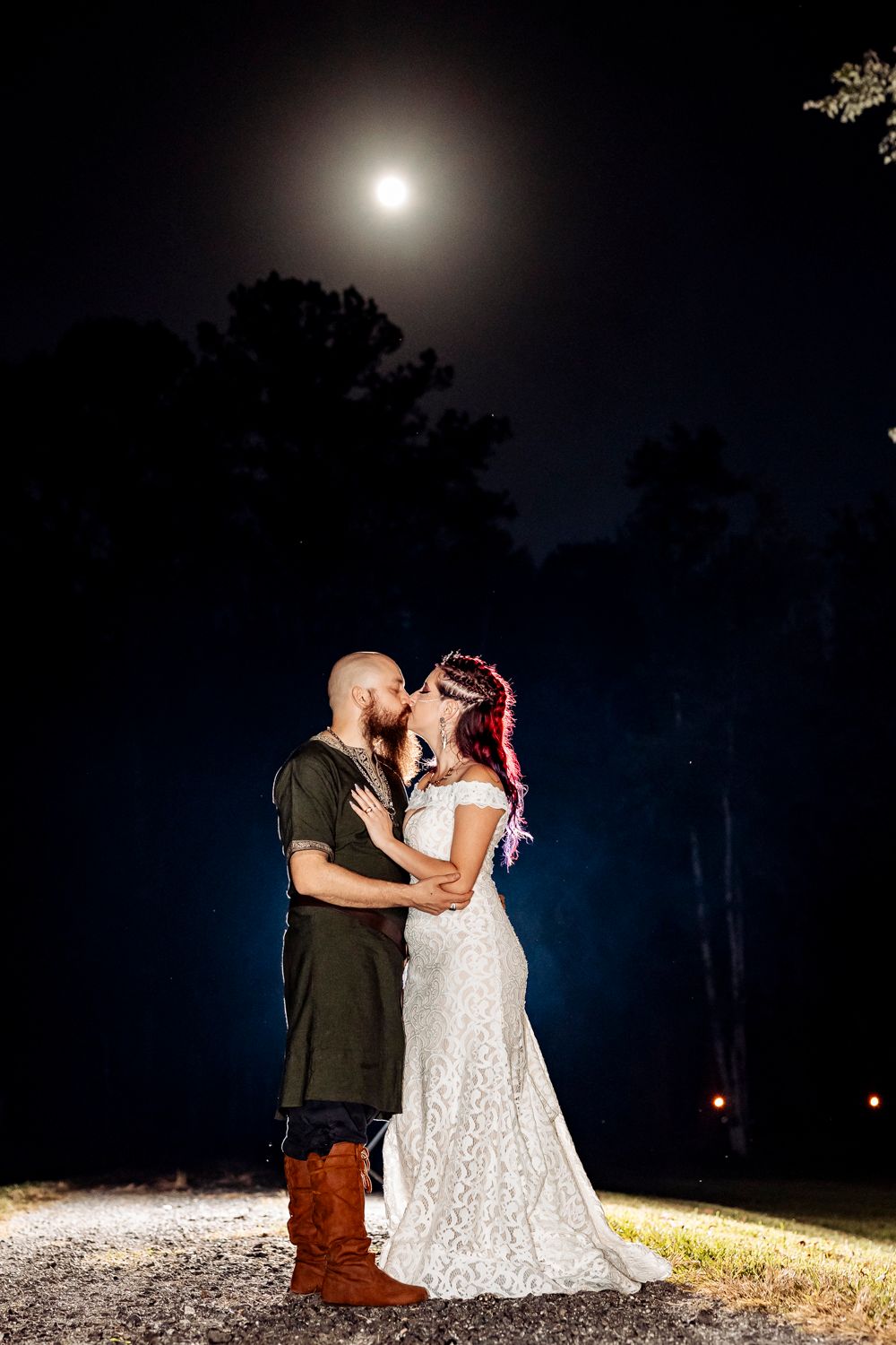 A romantic moonlit portrait of a couple embracing on a path under a full moon.