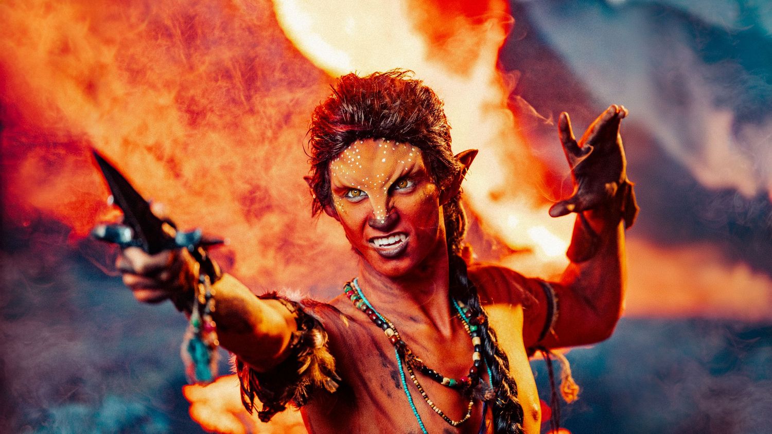 Dramatic fantasy character wielding weapons amid orange flames and smoke effects.