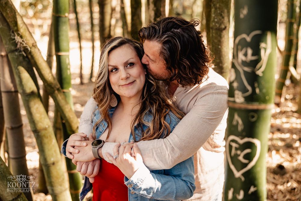 A tender moment shared between a couple in a bamboo forest setting.