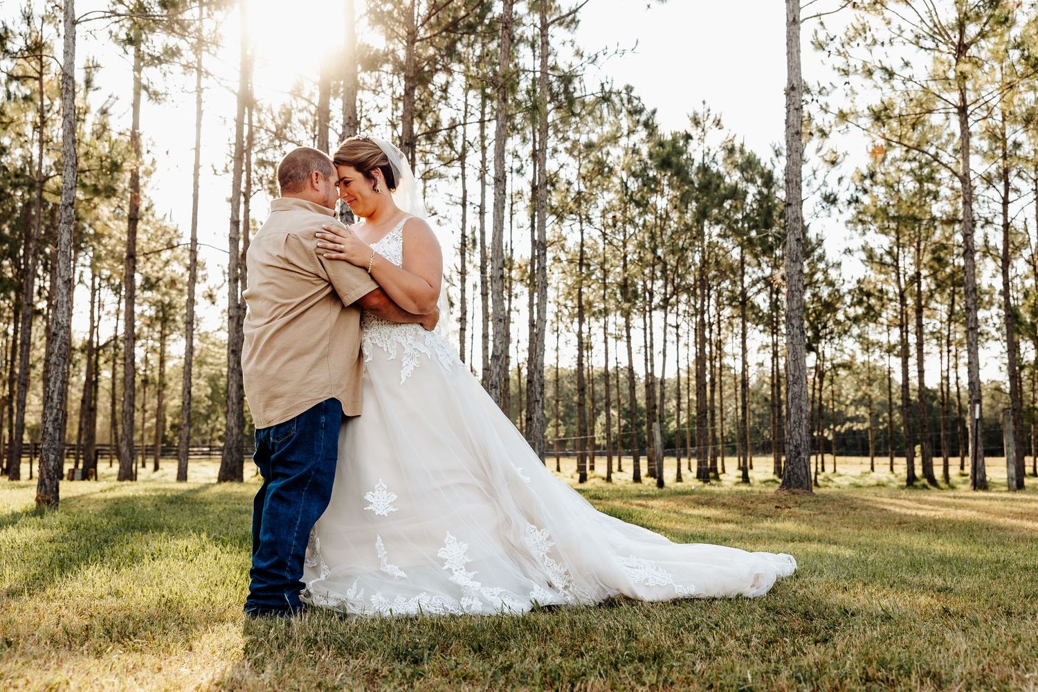 A romantic embrace between newlyweds in a sun-dappled pine forest setting.