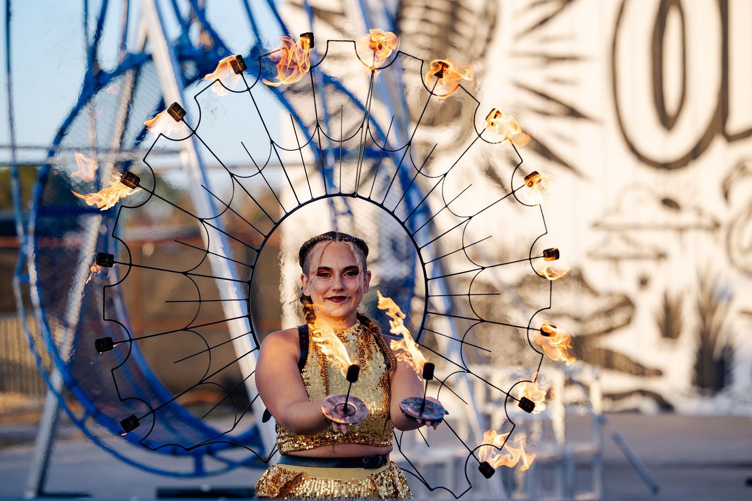 Performer in golden costume with elaborate light-adorned circular headdress at an outdoor festival.