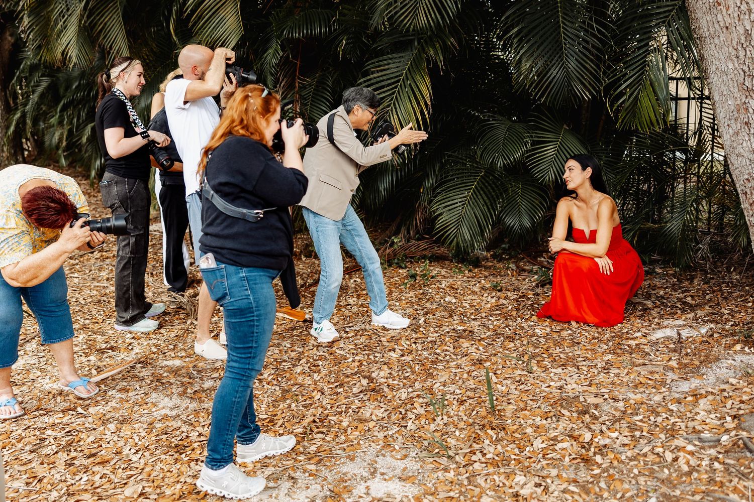 Professional photography team working together to capture shots of subject in red dress.